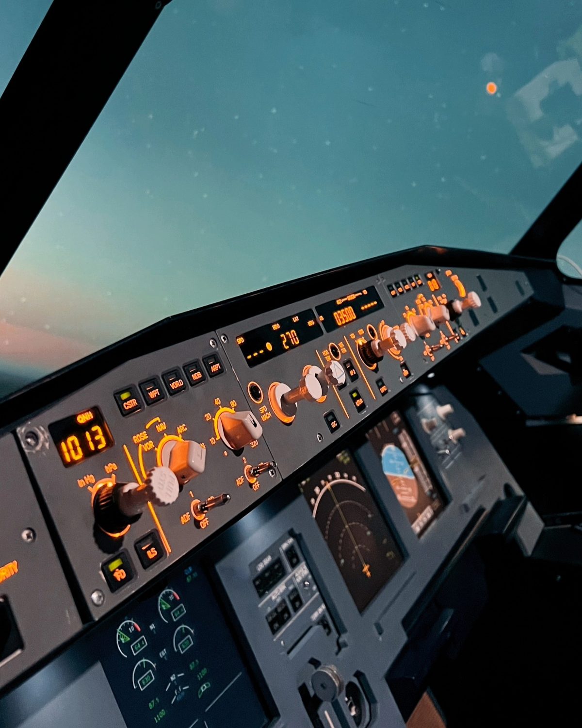Панель автопилота Airbus A320 в янтарной подсветке, за остеклением сумеречное небо